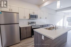 Thorold (Thorold Downtown) multi-family for rent - A kitchen with a refrigerator, microwave, oven, sink and cabinets.