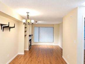 Surrey apartment for rent - A spacious room with wooden floors and a chandelier.
