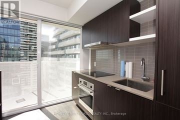 Toronto (Waterfront Communities) condo for rent - A modern kitchen with dark wood cabinets and a stainless steel sink and oven.