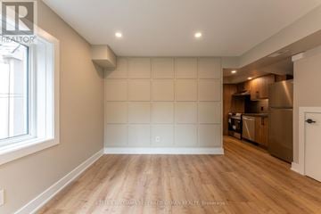 Toronto (Blake-Jones) apartment for rent - A spacious room with wooden flooring and a kitchen area in the background.