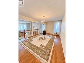 Burnaby apartment for rent - A large room with a rug in the middle and a chandelier hanging from the ceiling.