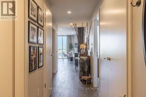 St. Catharines (Port Dalhousie) condo for rent - A hallway with a wooden floor and a series of framed pictures on the wall.