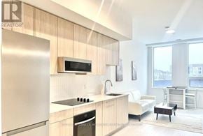 Oakville (Ga Glen Abbey) condo for rent - A modern kitchen with wooden cabinets and a stainless steel refrigerator.