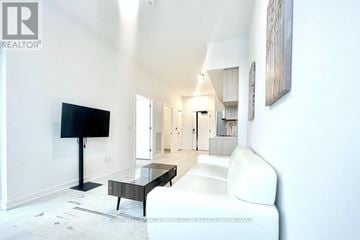 Oakville (Ga Glen Abbey) condo for rent - A living room with a white couch and a black television.