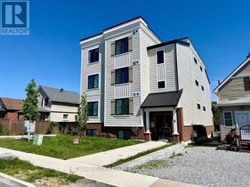 Thorold (Thorold Downtown) apartment for rent - A modern two-story building with a balcony on the second floor is surrounded by other houses.
