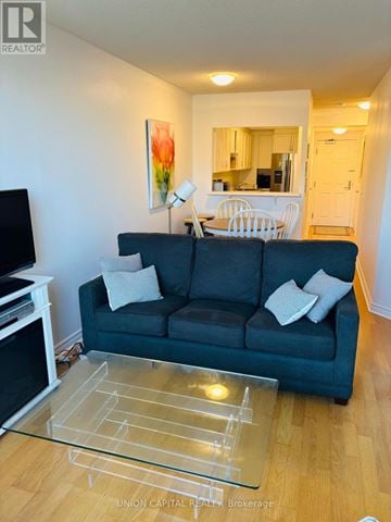 Toronto (Annex) condo for rent - A living room with a grey couch and a glass coffee table.