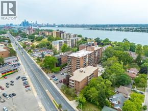 Windsor condo for rent - A cityscape with a river in the background and a parking lot in the foreground.