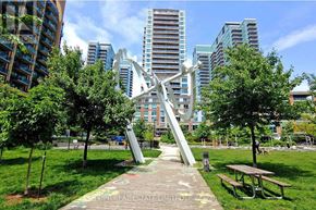 Toronto (Niagara) condo for rent - A playground with a slide and picnic tables in a park with trees and buildings in the background.