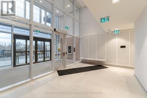 Toronto (Islington-City Centre West) condo for rent - The image shows a modern office lobby with a glass door entrance, a black mat on the floor, and a white wall with a green exit sign.