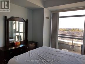 Markham (Unionville) condo for rent - A bedroom with a large bed, a wooden dresser with a mirror, and a window with a view of the city.