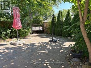St. Catharines (Ridley) apartment for rent - A backyard with a patio, a lawn mower, and a pink umbrella.