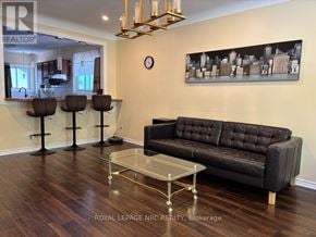 St. Catharines (Ridley) apartment for rent - A living room with a black couch, a glass coffee table, and a cityscape painting on the wall.