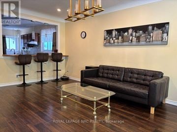 St. Catharines (Ridley) apartment for rent - A living room with a black couch, a glass coffee table, and a cityscape painting on the wall.