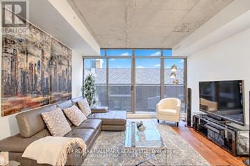 Toronto (Waterfront Communities) condo for rent - A living room with a large couch and a painting on the wall.