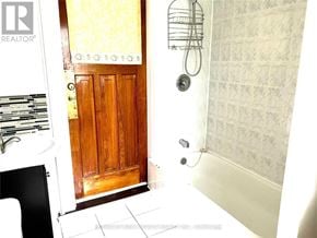 Toronto (South Riverdale) apartment for rent - A bathroom with a wooden door and a tiled wall.