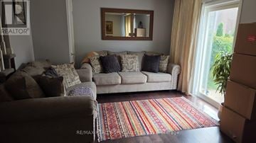 Milton (Co Coates) apartment for rent - A living room with a couch, a rug, and a mirror on the wall.