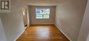 Oakville (Co Central) apartment for rent - A room with wooden floors and a window showing a parking lot outside.