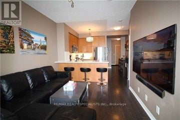 Mississauga (City Centre) condo for rent - A living room with a black leather couch and a flat screen TV mounted on the wall.