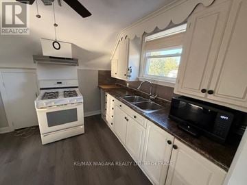 Thorold (Thorold Downtown) apartment for rent - A kitchen with white cabinets and a black microwave.