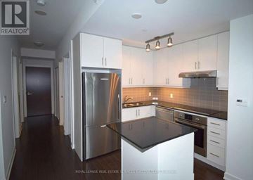 Toronto (Waterfront Communities) condo for rent - A modern kitchen with white cabinets and stainless steel appliances.