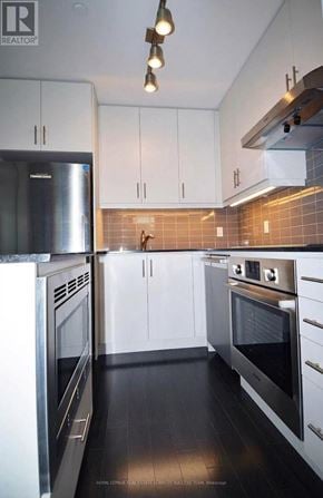 Toronto (Waterfront Communities) condo for rent - A modern kitchen with stainless steel appliances and white cabinets.