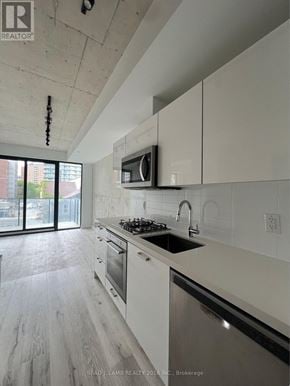 Toronto (Moss Park) condo for rent - A modern kitchen with white cabinets and a black stove top.
