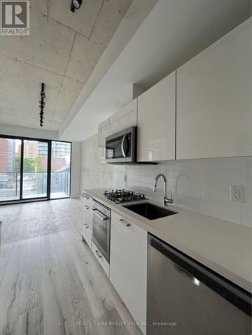 Toronto (Moss Park) condo for rent - A modern kitchen with white cabinets and a black stove top.