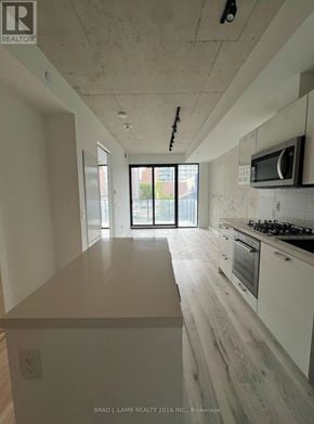Toronto (Moss Park) condo for rent - A kitchen with white cabinets and a wooden floor.
