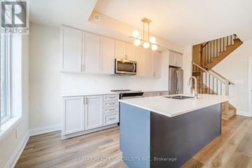 Milton (Cb Cobban) townhouse for rent - A kitchen with white cabinets and a blue island.