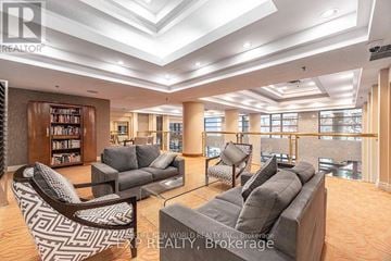 Toronto (Bay Street Corridor) condo for rent - A living room with a grey couch and a black and white patterned chair.
