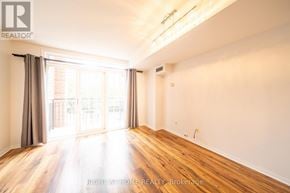 Toronto (Niagara) townhouse for rent - A spacious room with wooden floors and a large window with curtains.