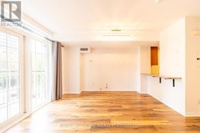 Toronto (Niagara) townhouse for rent - A spacious room with wooden flooring and white walls.