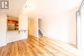 Toronto (Niagara) townhouse for rent - A spacious room with wooden flooring and a staircase leading to another room.