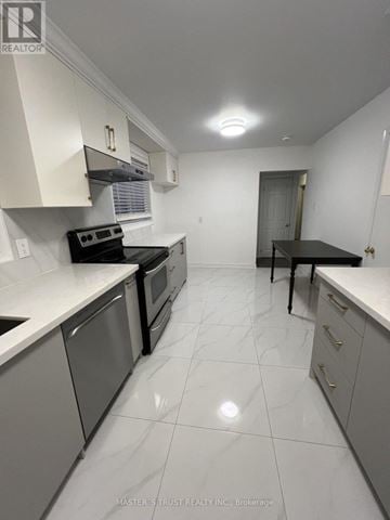 Toronto (Woburn) apartment for rent - A white kitchen with a black counter and stove.