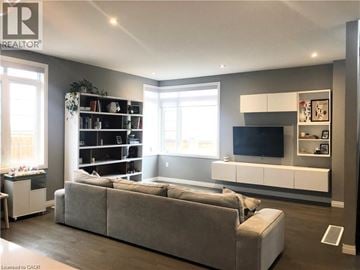 Stoney Creek townhouse for rent - A living room with a grey couch and a television on a white cabinet.