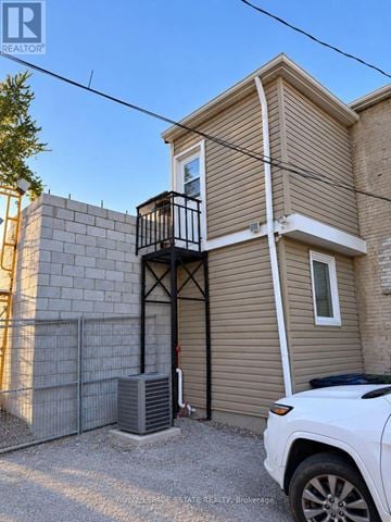 Toronto (The Beaches) apartment for rent - A white car is parked in front of a two-story house with a balcony.