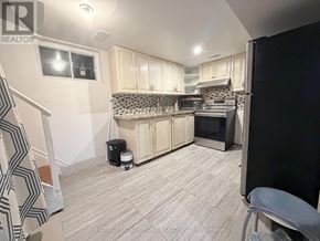 Toronto (Wexford-Maryvale) apartment for rent - A kitchen with white cabinets and a black refrigerator.