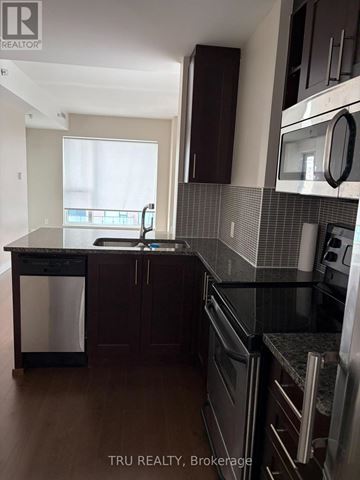 Ottawa condo for rent - A kitchen with dark wood cabinets and black appliances.