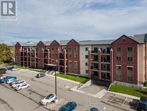 New Tecumseth (Alliston) condo for rent - A parking lot in front of a multi-story brick building.