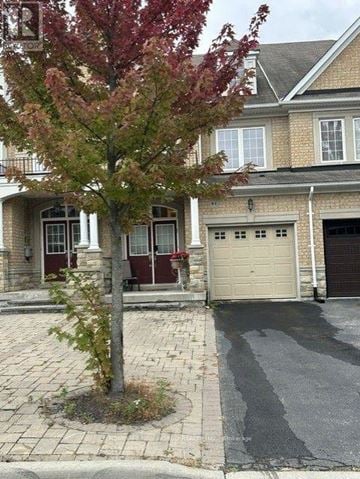 Vaughan (Patterson) townhouse for rent - A tree with red leaves stands in front of a house with a garage.