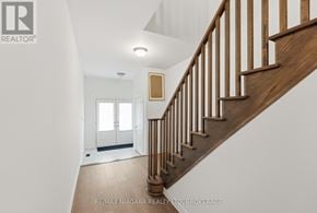 Thorold (Rolling Meadows) townhouse for rent - A staircase with a wooden handrail and white balusters leads to a white door.