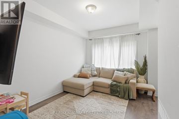 Thorold (Rolling Meadows) townhouse for rent - A living room with a beige couch and a rug.