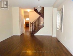 Richmond Hill (Oak Ridges) apartment for rent - A spacious room with wooden floors and a staircase leading to another level.