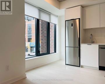 Toronto (Junction Area) condo for rent - A modern kitchen with a stainless steel refrigerator and white cabinets.