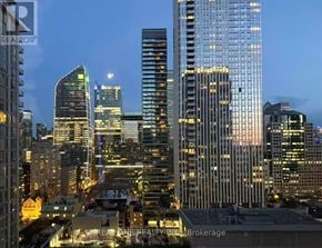 Toronto (Waterfront Communities) condo for rent - A cityscape at dusk with buildings illuminated from within.