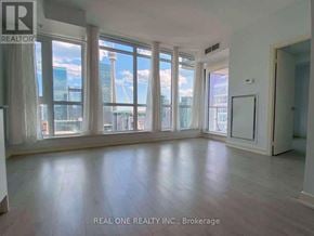 Toronto (Waterfront Communities) condo for rent - A spacious room with large windows overlooking a cityscape.