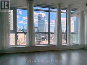 Toronto (Waterfront Communities) condo for rent - A room with large windows overlooking a cityscape.