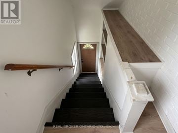 New Tecumseth (Beeton) duplex for rent - A staircase with a wooden handrail and a white brick wall.