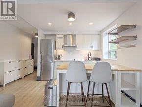 Toronto (Woodbine Corridor) condo for rent - A modern kitchen with white cabinets and a wooden island.