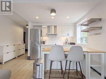 Toronto (Woodbine Corridor) condo for rent - A modern kitchen with white cabinets and a wooden island.